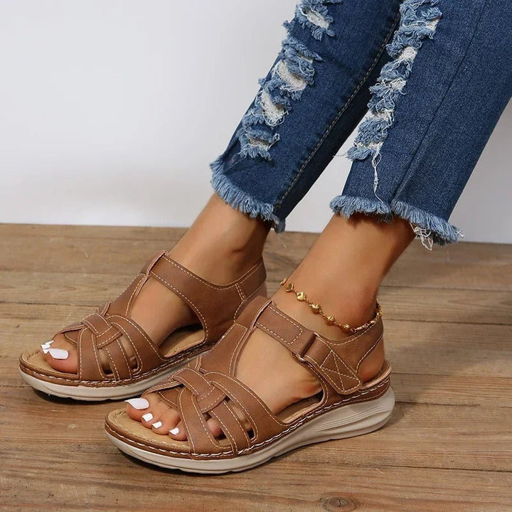 Brown open-toe flat sandals with interlaced cutout upper and back strap