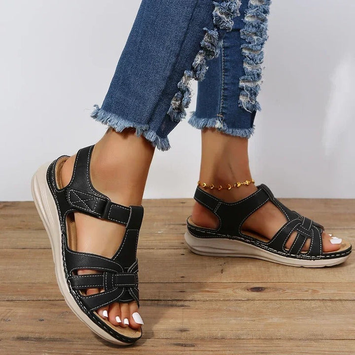 Black open-toe flat sandals with interlaced cutout upper and back strap